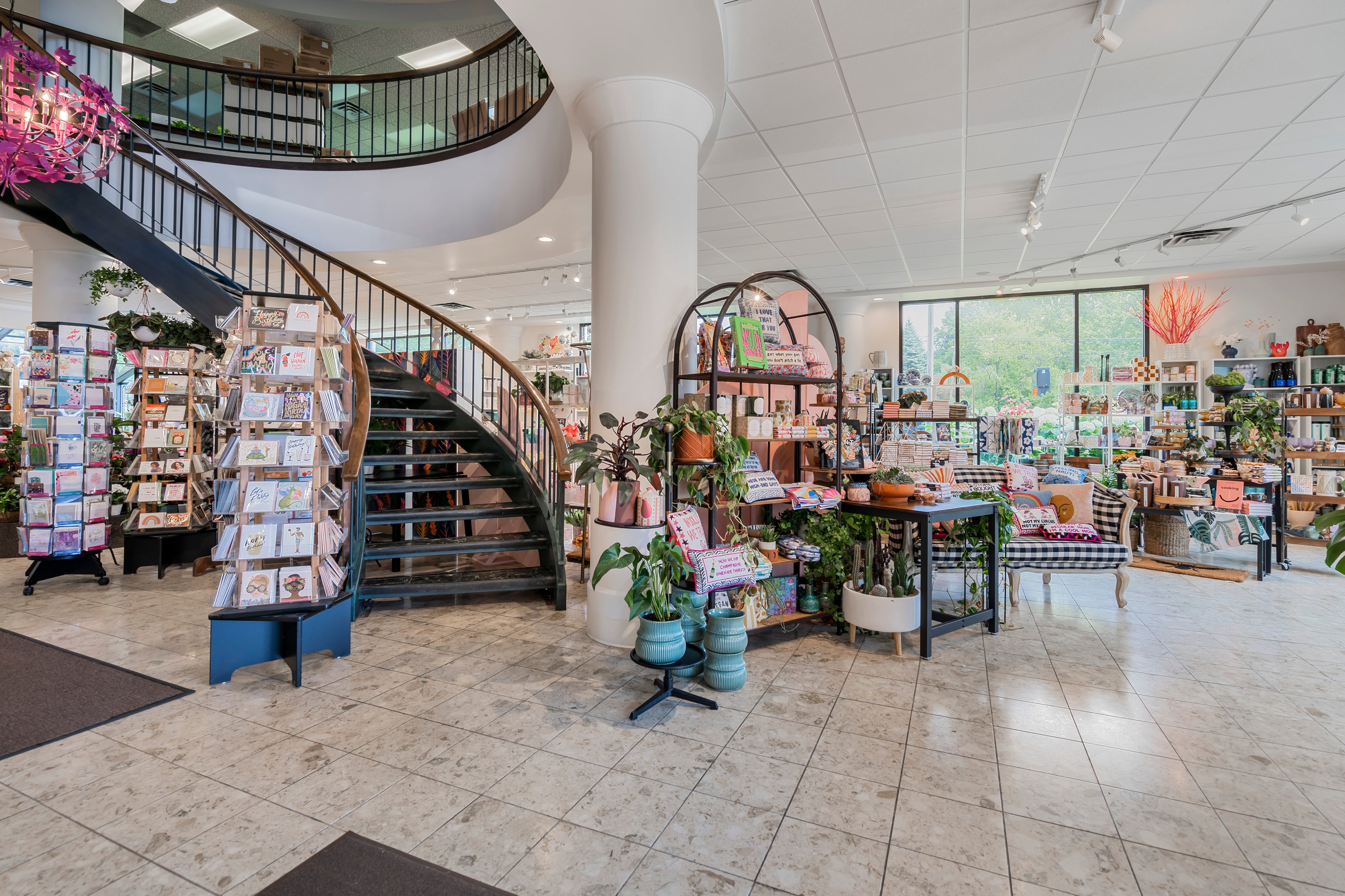 Interior of a store with a spiral staircase, bookshelves, and various products.