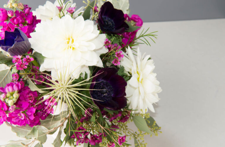 Bouquet of flowers with white, purple, and green colors on a light gray background